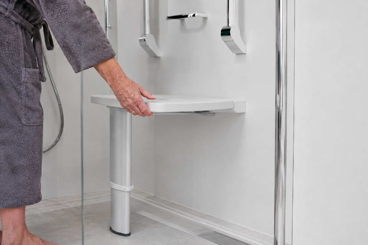A white fold-down shower seat fitted inside a modern walk-in shower